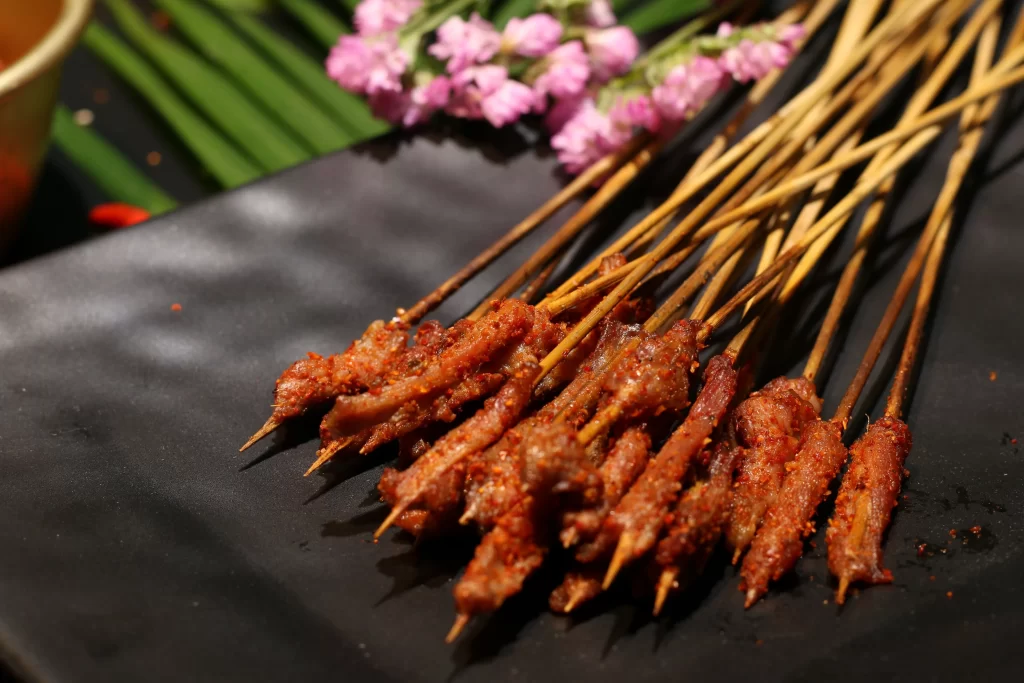 Golden Brown Pork Skewers with Reddish Marinade on Black Plate