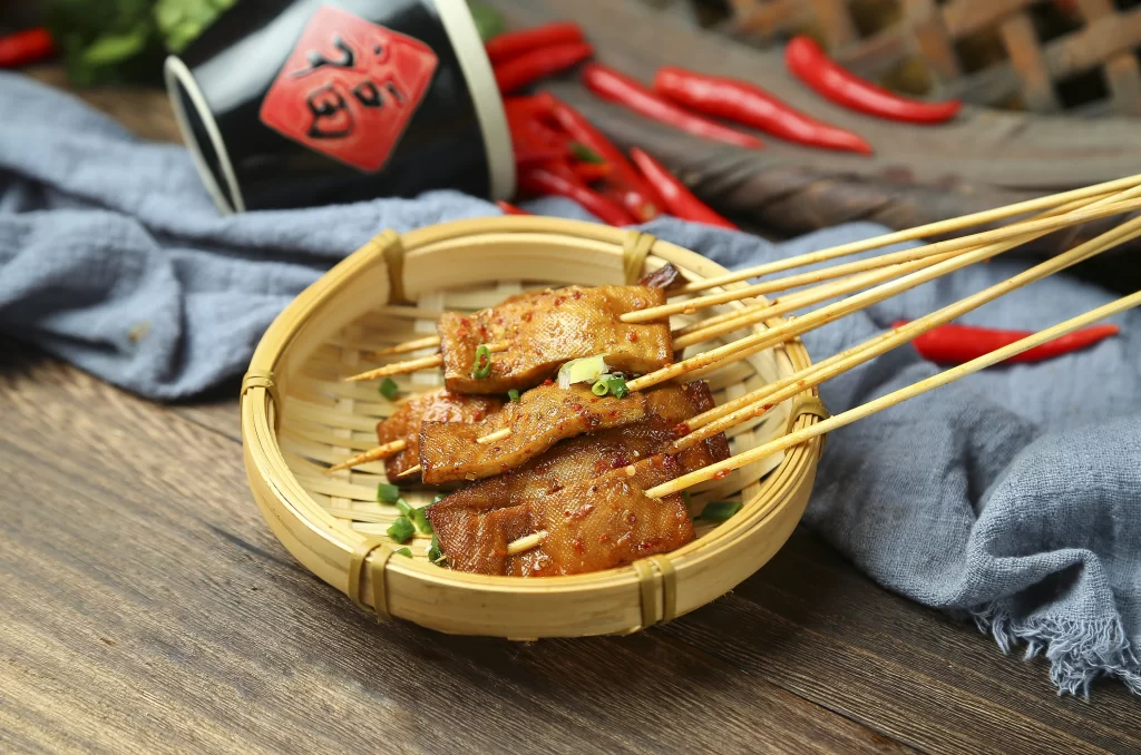 Golden Brown Pork Skewers with Reddish Sauce and Green Garnish
