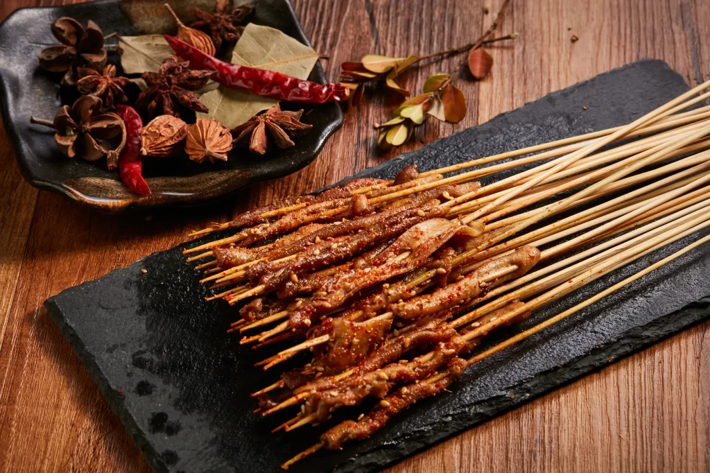 Golden Brown Pork Skewers with Reddish Spices on Slate Plate