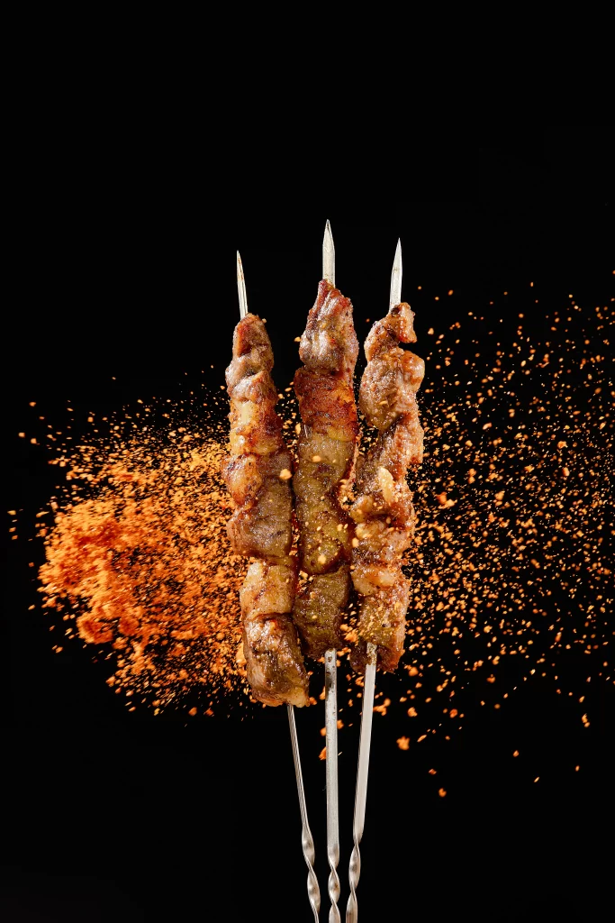 Golden Brown Pork Skewers with Spices Flying in Air