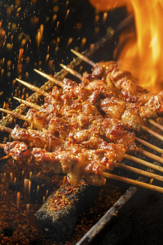 Golden Brown Pork Skewers with Spices on Black Grill