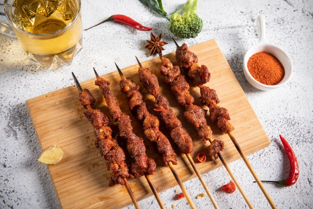 Golden Brown Pork Skewers with Spices on Light Wood Board