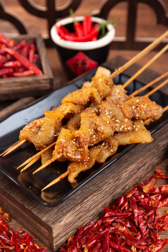 Golden Brown Pork Skewers with Spicy Garnish on Black Plate 九月(32).