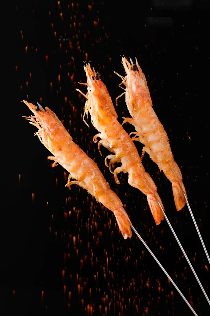 Golden Brown Shrimp Skewers with Charred Edges on Dark Plate