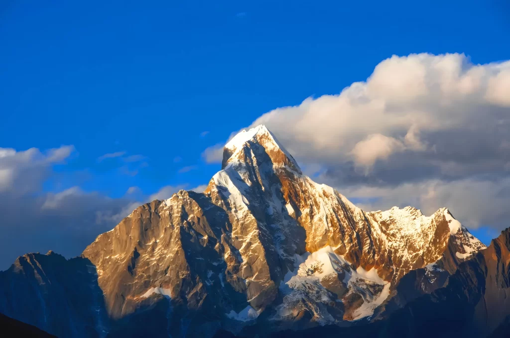golden hour blue sky white clouds snow capped peaks rocky