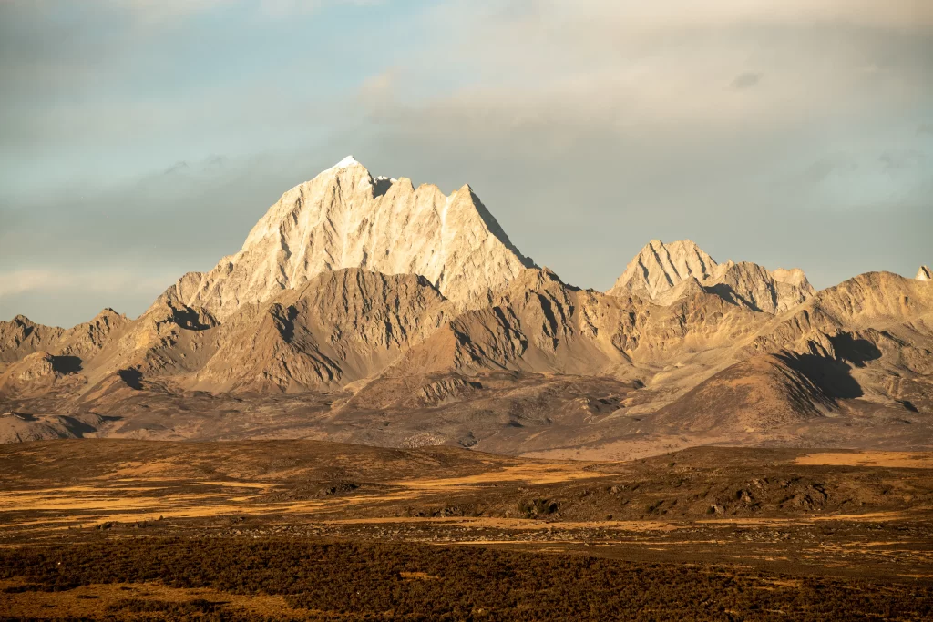 golden hour earthy snow capped peaks rocky terrain rolling hills