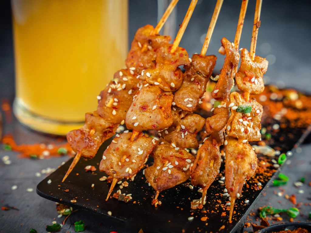 Golden Pork Skewers with Sesame and Green Onion Garnish