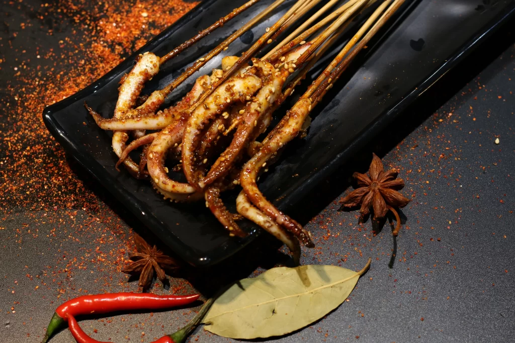 Grilled Octopus Skewers Spicy Sauce Charred Edges Black Plate