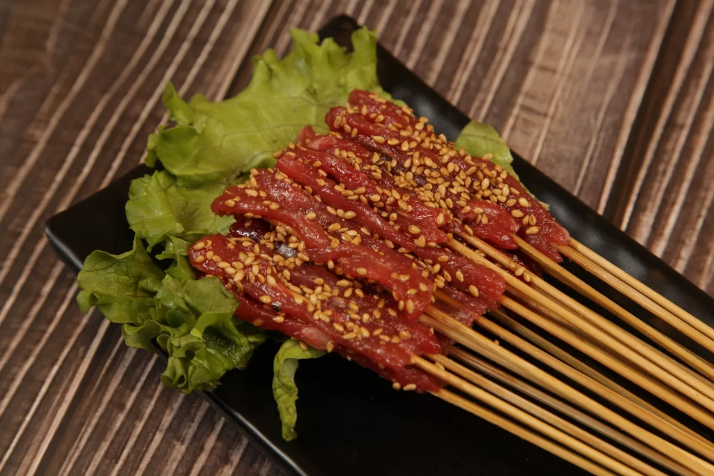 Marinated Beef Skewers Sesame Garnish Fresh Lettuce Plated