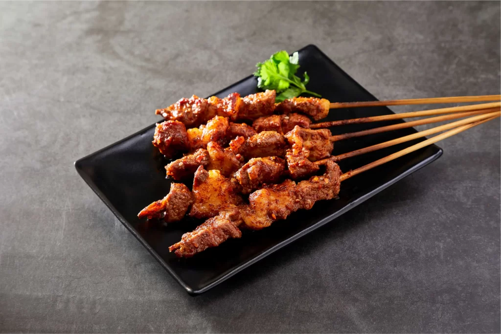 Spicy Beef Skewers Charred Crust Garnished with Cilantro Black Plate