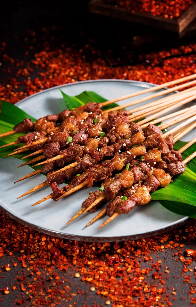 Spicy Beef Skewers Charred Crust Green Garnish White Plate