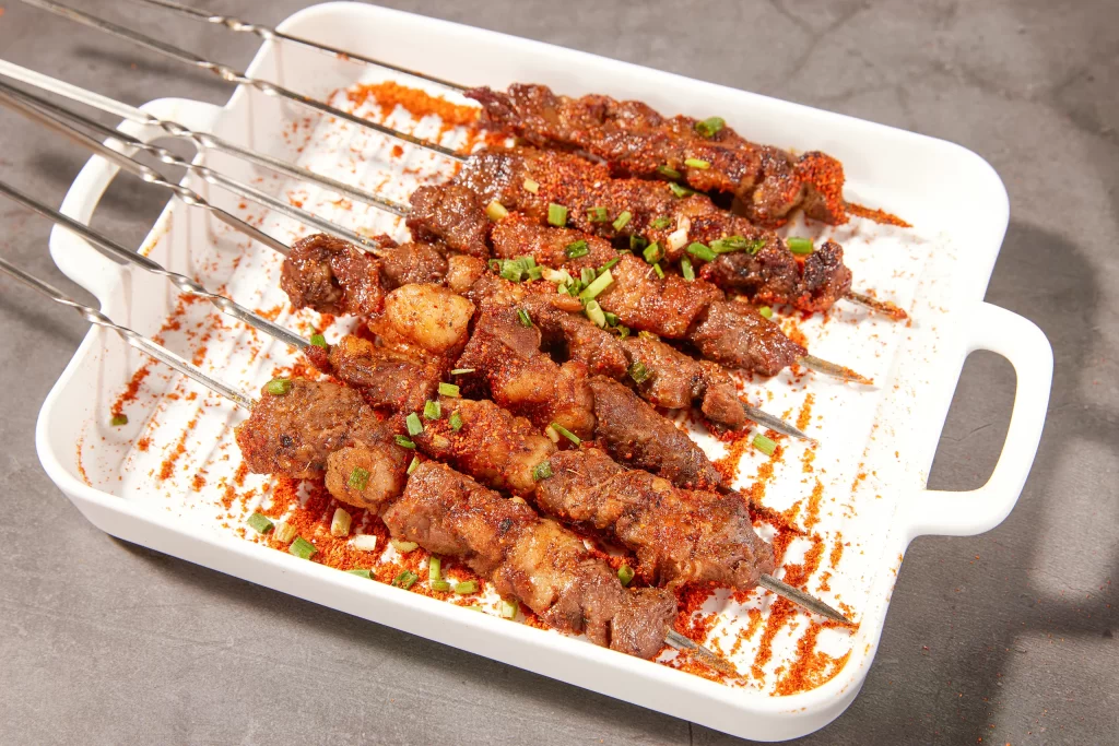 Spicy Beef Skewers Red Pepper Garnish White Plate