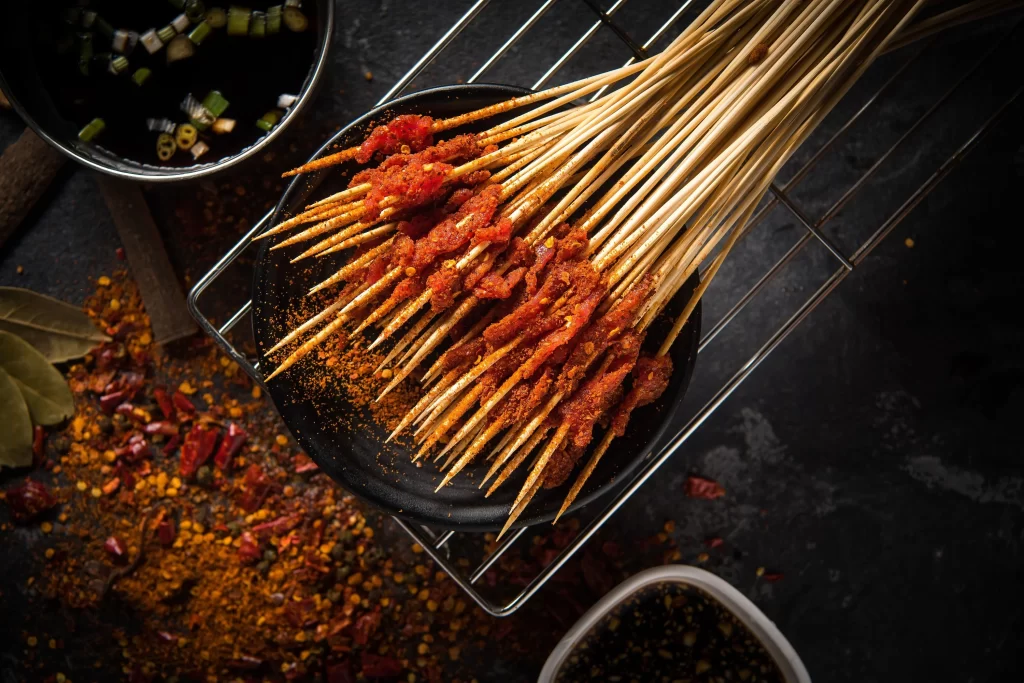 Spicy Beef Skewers Red Sauce Charred Tips Black Plate