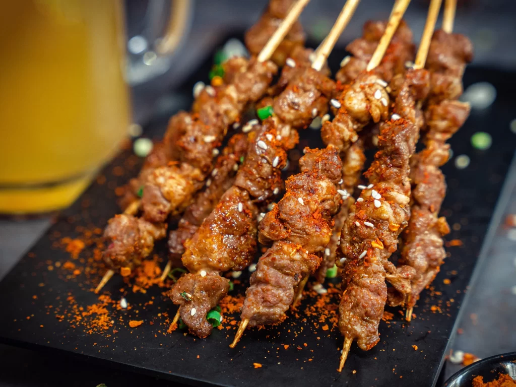 Spicy Beef Skewers Sesame Seeds Red Pepper Flakes Black Plate