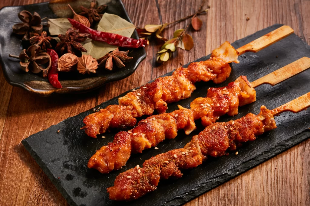 Spicy Chicken Skewers Red Sauce Sesame Garnish Slate Plate