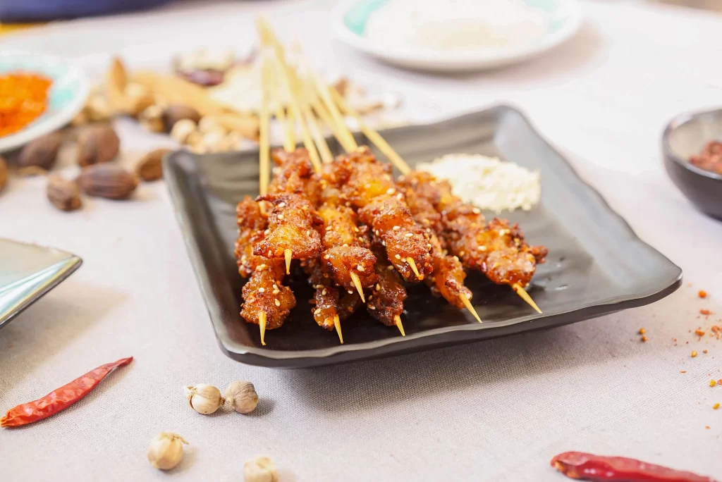 Spicy Chicken Skewers Sesame Garnish Black Plate