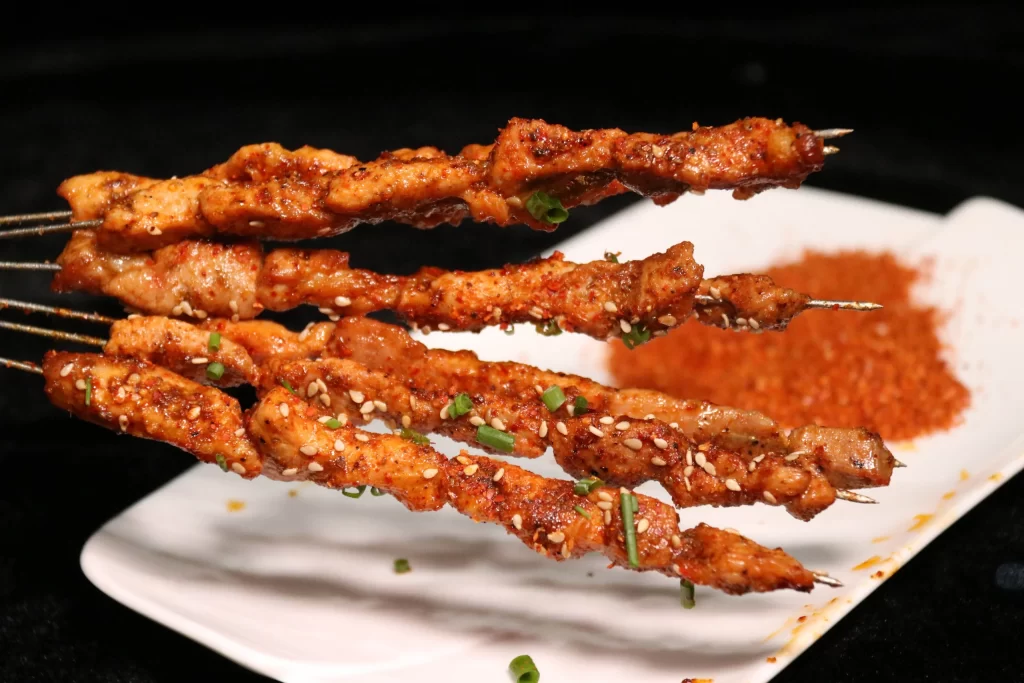 Spicy Chicken Skewers Sesame Garnish Red Sauce Plated