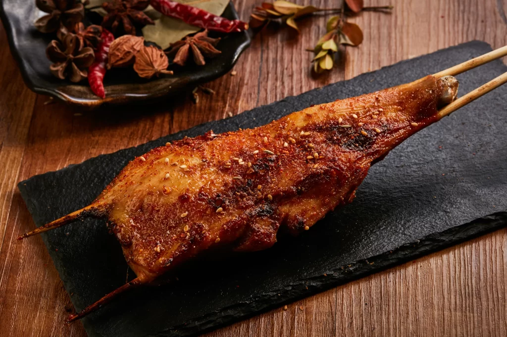 Spicy Grilled Chicken Leg Charred Crust Sesame Garnish Slate Plate