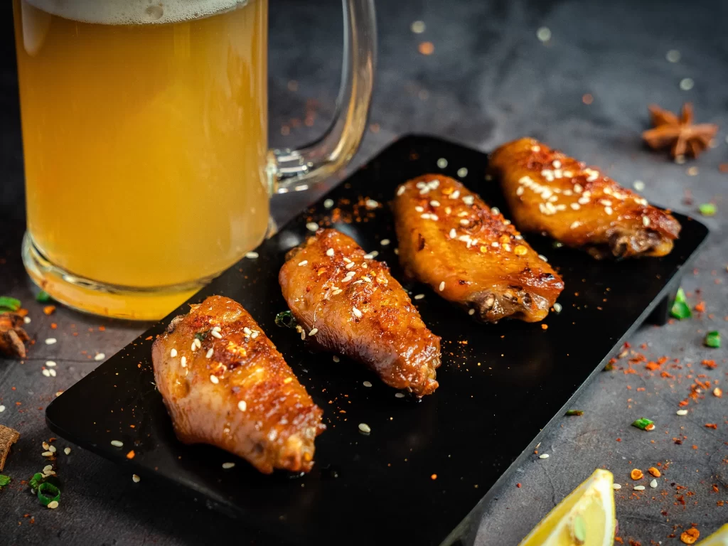 Spicy Grilled Chicken Wings Sesame Garnish Black Plate