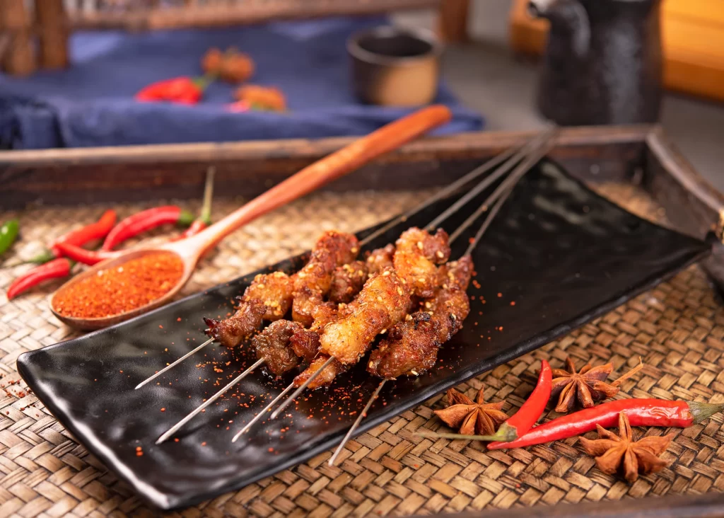 Spicy Pork Skewers Charred Crust Red Pepper Flakes Black Plate