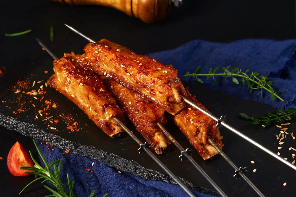 Spicy Pork Skewers Charred Crust Sesame Garnish Black Slate