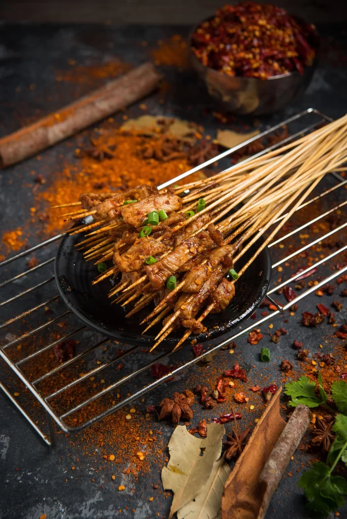 Spicy Pork Skewers Cumin Powder Green Onion Garnish Black Plate
