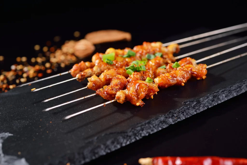 Spicy Pork Skewers Green Onion Garnish Black Slate Plate