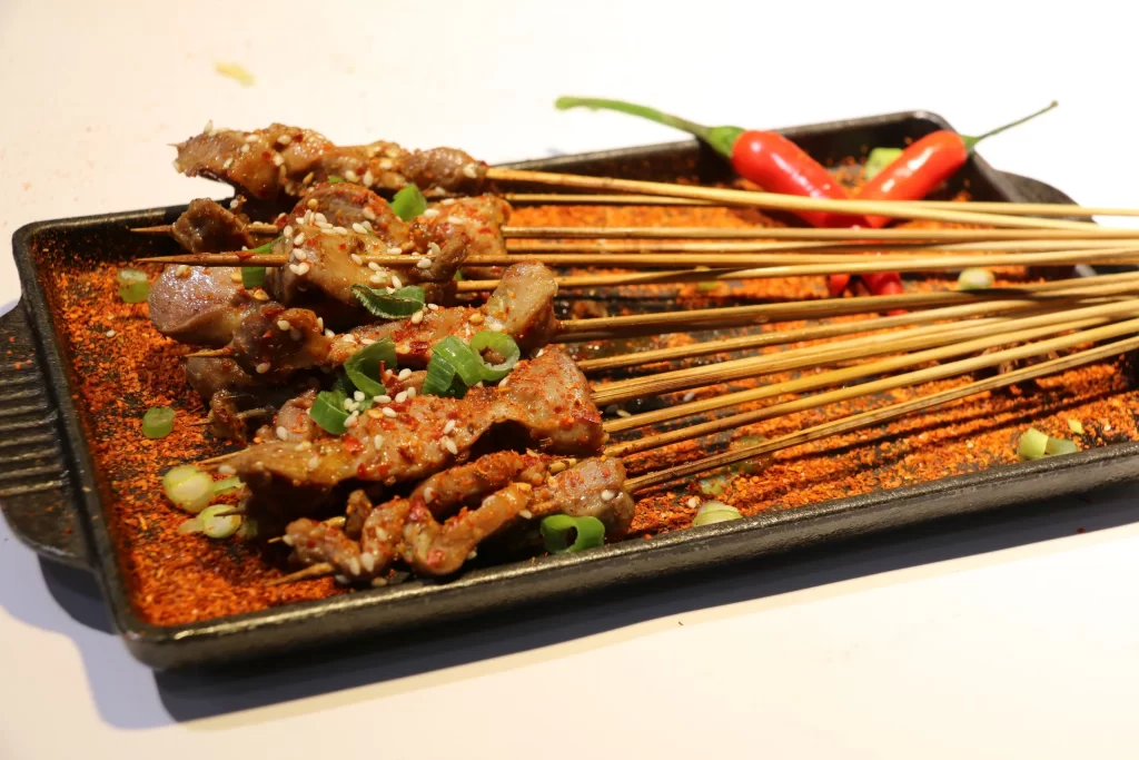 Spicy Pork Skewers Red Chili Garnish Black Plate