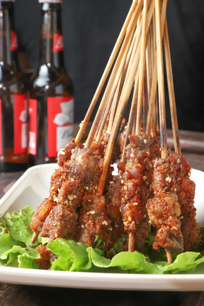 Spicy Pork Skewers Red Chili Sesame Garnish White Plate