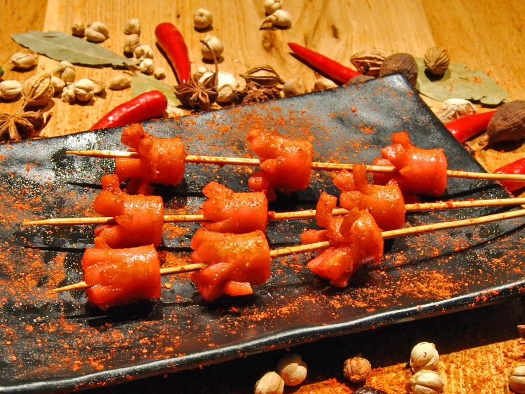Spicy Pork Skewers Red Paprika Charred Edges Black Plate