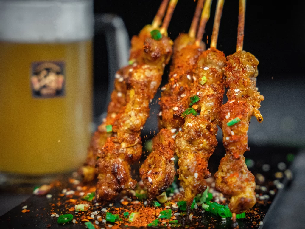 Spicy Pork Skewers Sesame Green Onion Black Plate