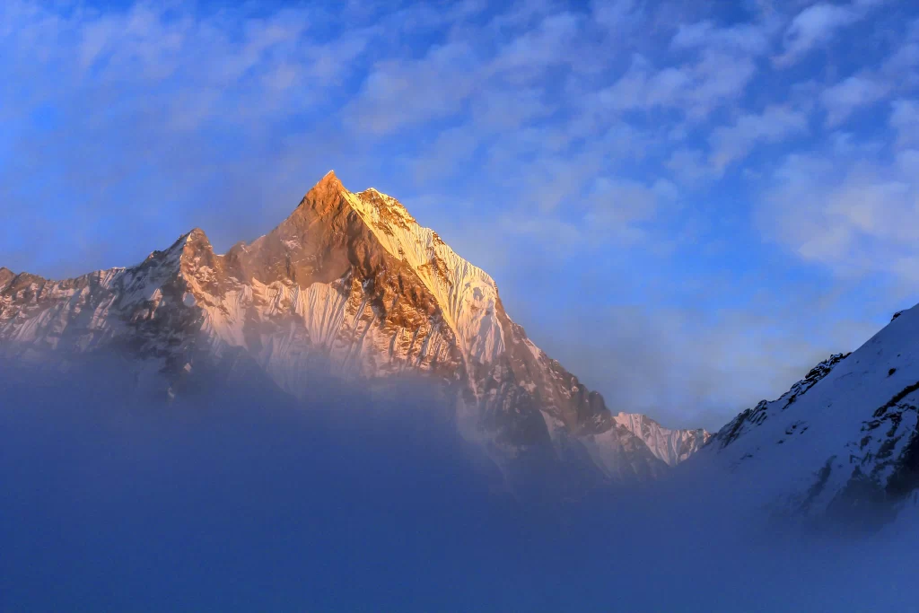 sunrise golden snow-capped peaks blue sky white clouds misty valleys