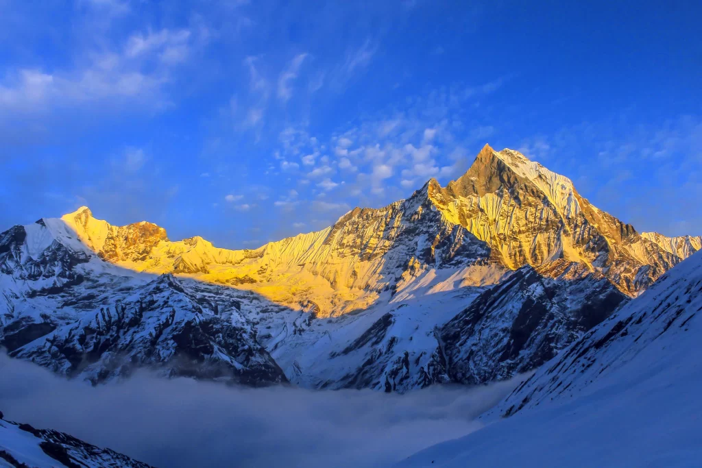 sunrise snow-capped peaks golden light blue sky white clouds mountain
