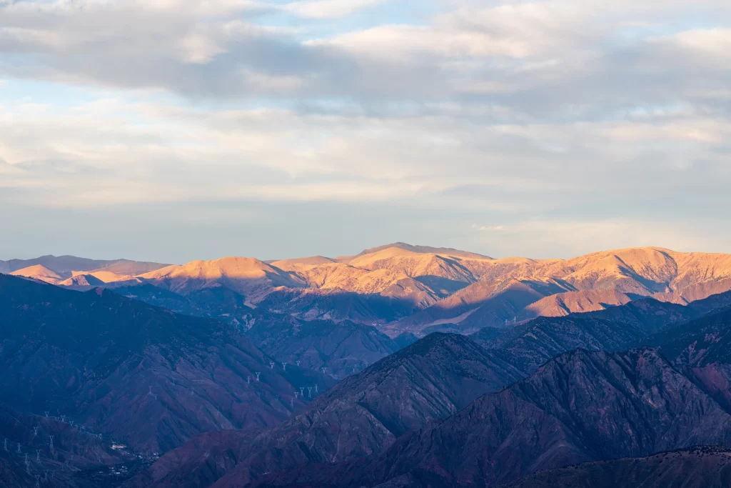 sunset golden deep shadows mountain ridges layered peaks clear sky