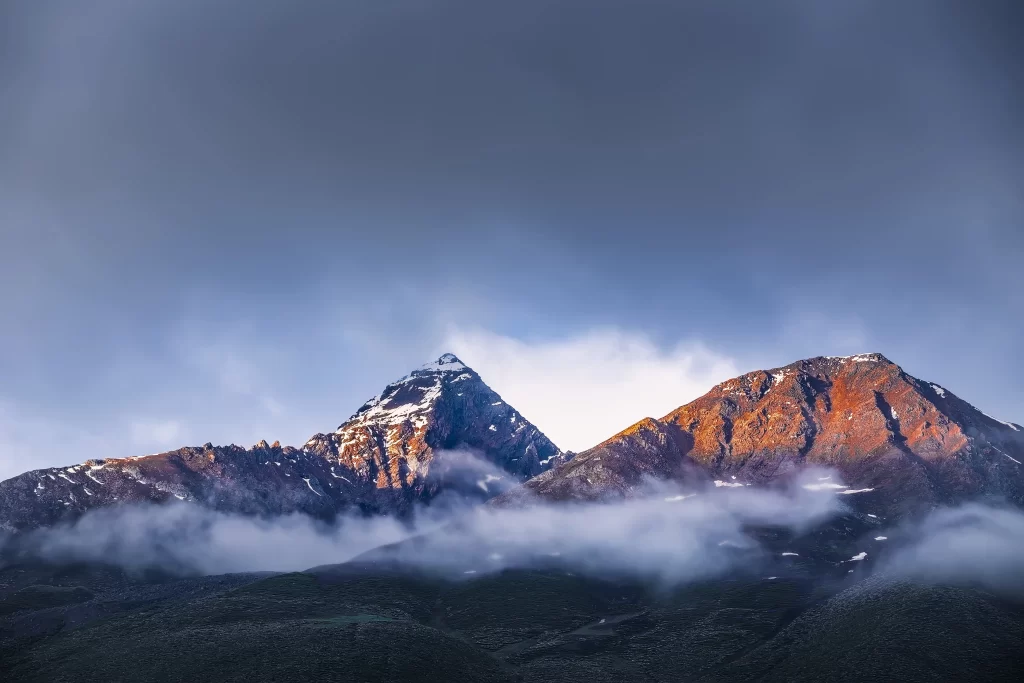 sunset golden orange red teal blue ridge snow peak clouds