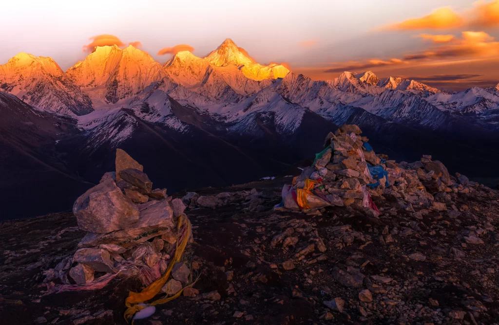 sunset golden orange snow-capped rugged mountain prayer flags rocky terrain