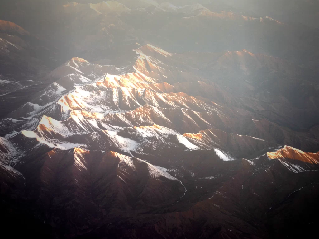 sunset golden orange snow-capped rugged mountain range valleys shadows