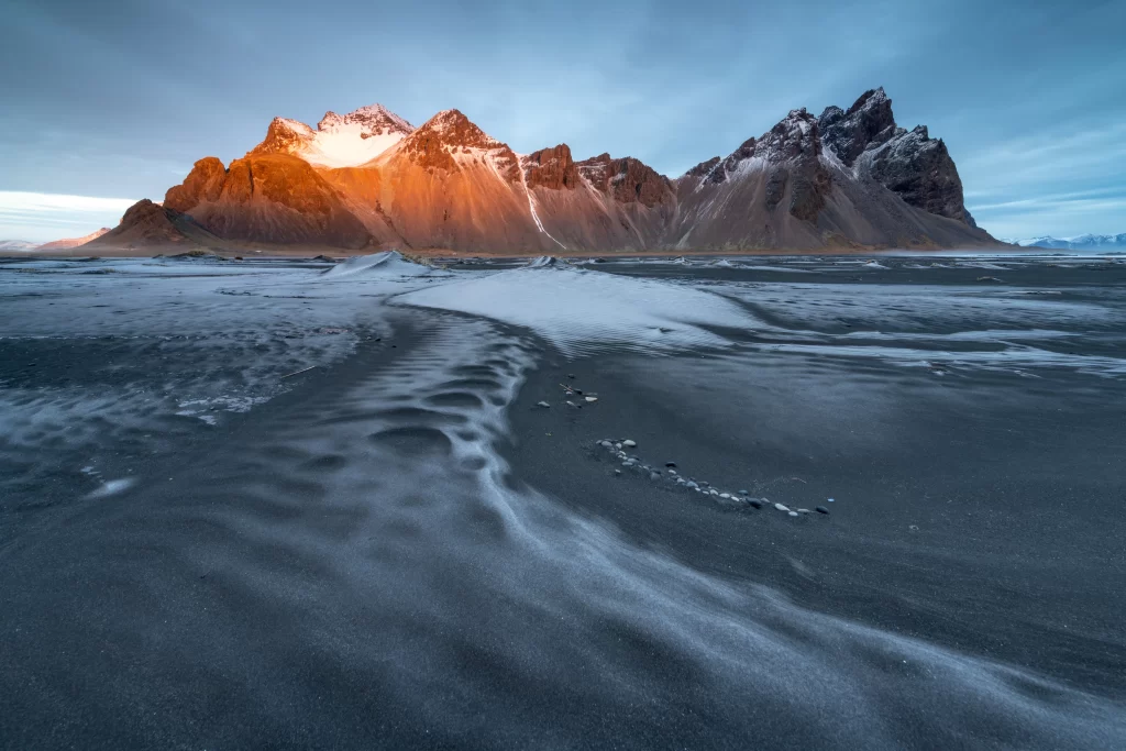 sunset golden rugged peaks snow-capped blue sky textured sand tranquil