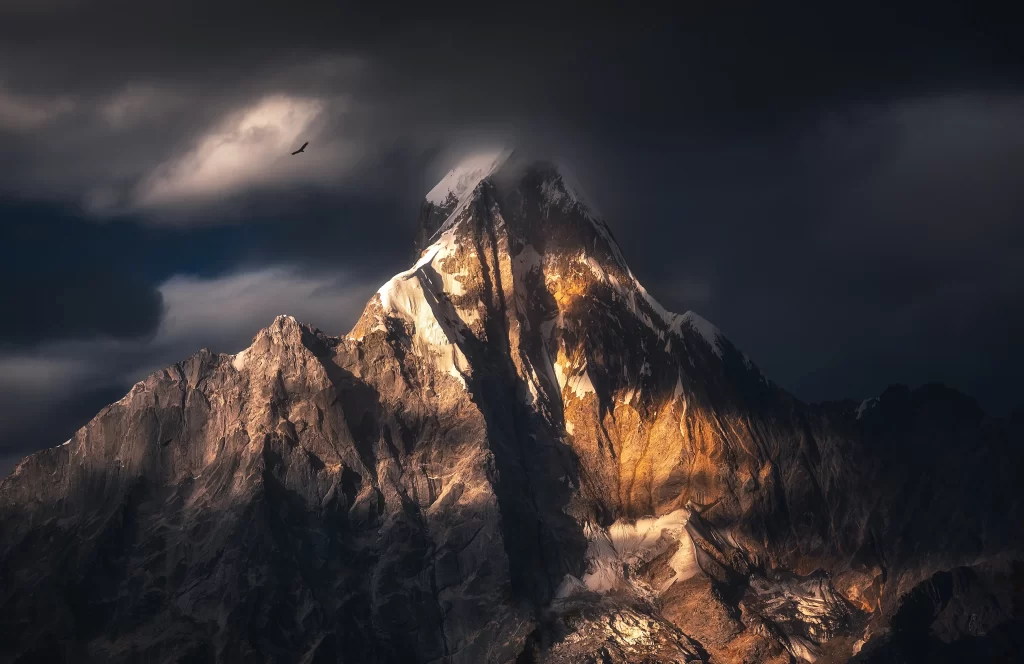 sunset golden rugged peaks dramatic clouds solitary bird shadowed valleys
