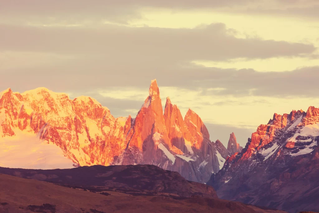sunset golden snow-capped peaks rugged terrain dramatic sky serene majestic