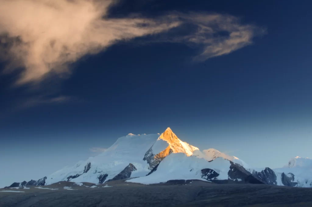sunset golden snow-capped peaks deep blue sky wispy clouds rugged