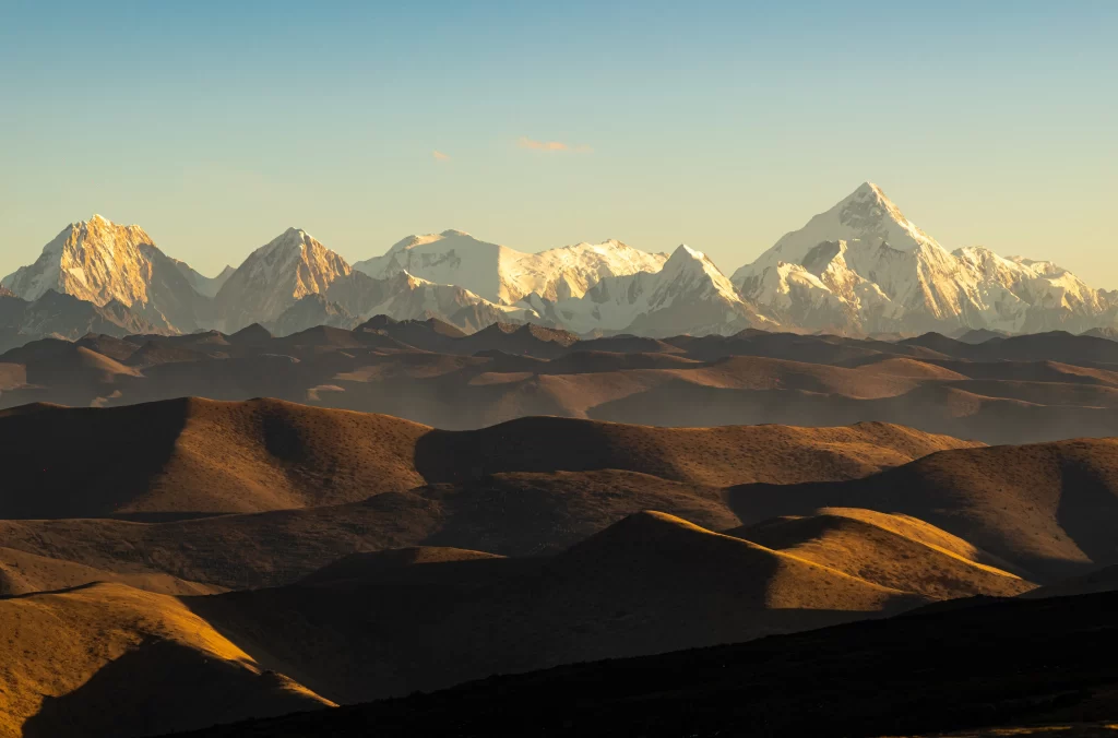 sunset golden snow-capped peaks rolling hills clear sky serene tranquil
