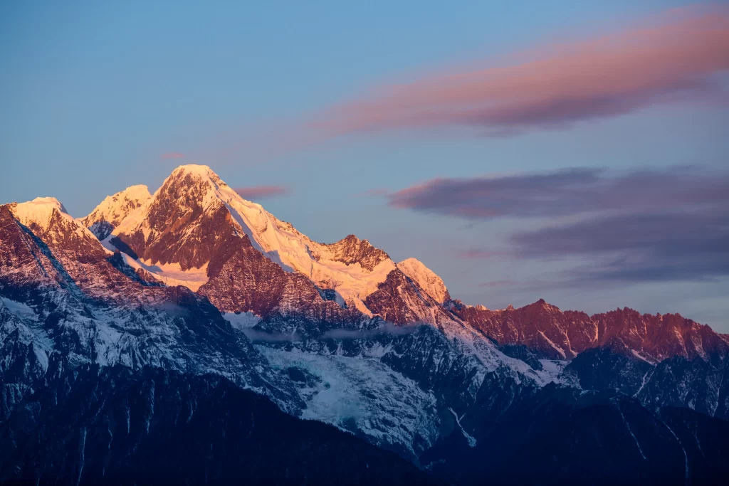 sunset golden snow-capped peaks deep blue sky pink clouds rugged