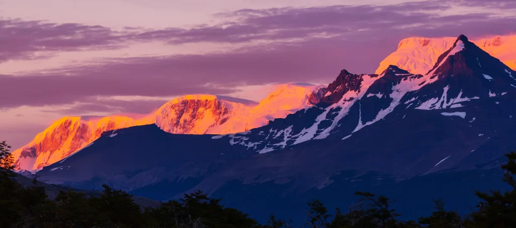 sunset golden snow-capped peaks purple sky rugged terrain mountain ridges