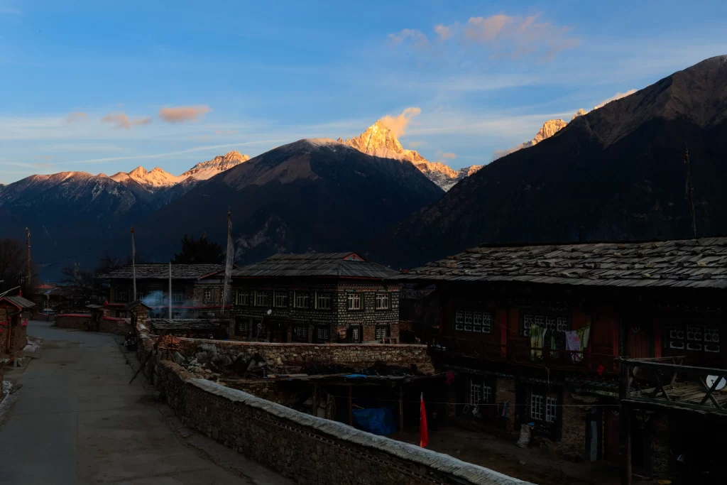 sunset golden snow-capped peaks traditional buildings stone walls rustic village