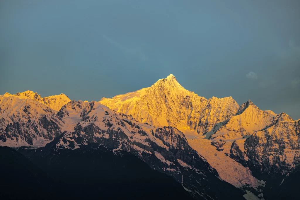 sunset golden snow-capped peaks clear sky mountain ridges dramatic shadows