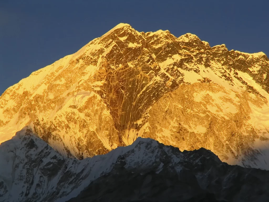 sunset golden snow-capped peaks dramatic shadows clear sky rugged terrain