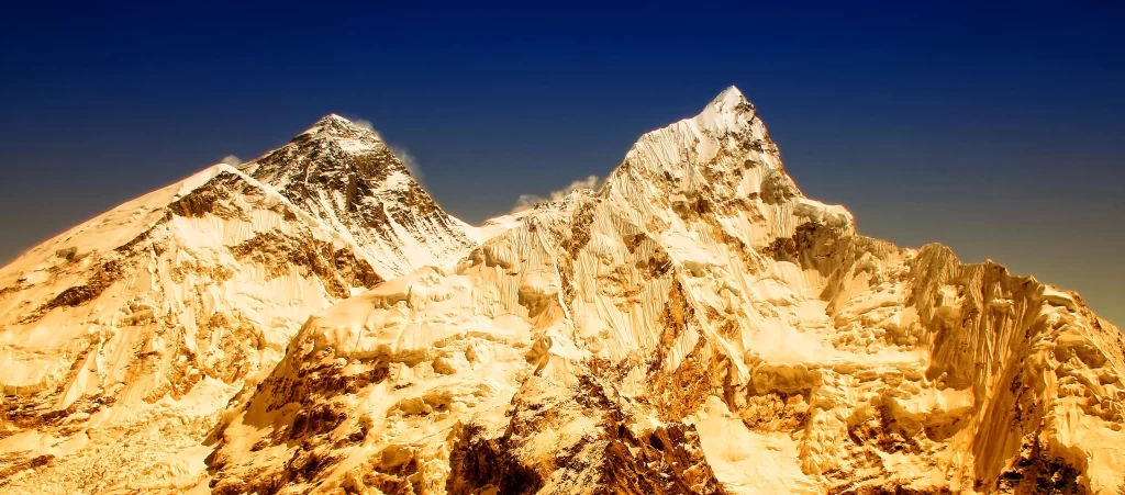 sunset golden snow-capped peaks clear sky rugged terrain sharp ridges