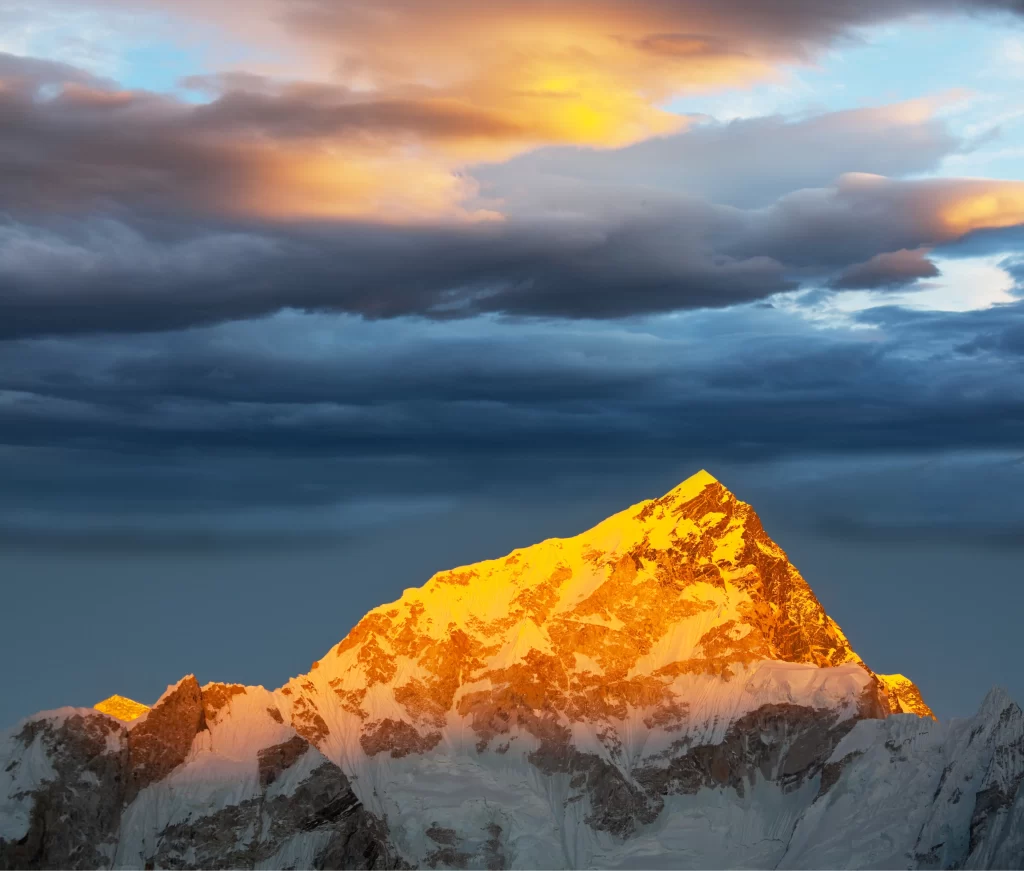 sunset golden snow-capped peaks dramatic clouds blue sky rugged terrain