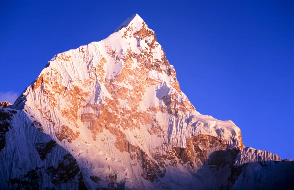sunset golden snow-capped peaks deep blue sky rugged terrain sharp